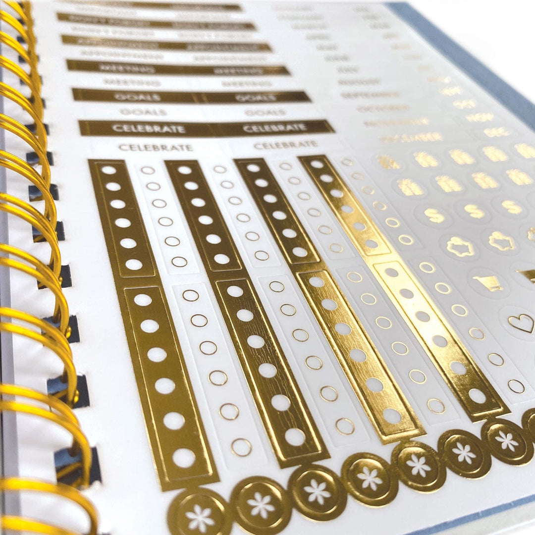 PL-6000E - Planner Organizer Undated - Wild and Free Undated - Spiral-bound planner page with gold and white decorative tracker strips featuring circles and ornamental designs, bound with yellow spiral coil