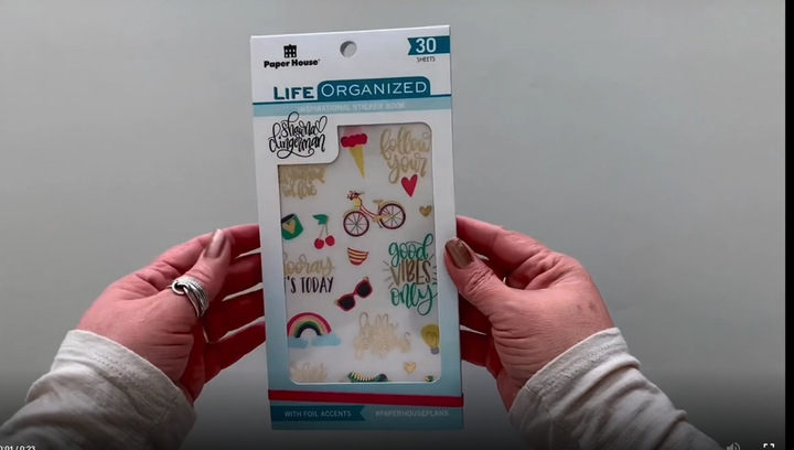 Female hands pick up and flip through the pages of the "Shawna Clingerman" planner stickers booklet to show each page of stickers in detail. There are thirty pages featuring colorful inspirational sayings and illustrations in this sticker book by Paper House Productions.