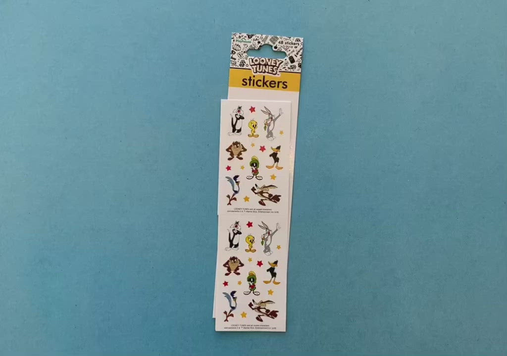 female hands display stickers featuring looney tunes characters, on blue background with package.